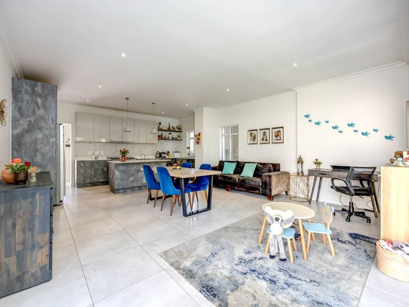 Spacious open-plan living area featuring a modern kitchen with island, sleek cabinetry, and large format floor tiles throughout.