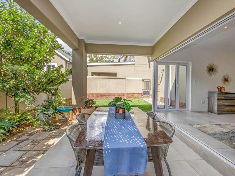 A covered outdoor patio featuring tiled flooring and recessed lighting, seamlessly connecting to the interior living space through large sliding glass doors.