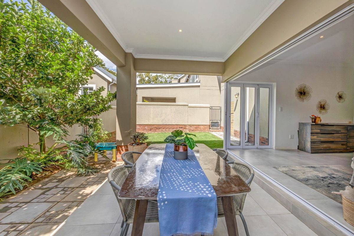 A covered outdoor patio featuring tiled flooring and recessed lighting, seamlessly connecting to the interior living space through large sliding glass doors.