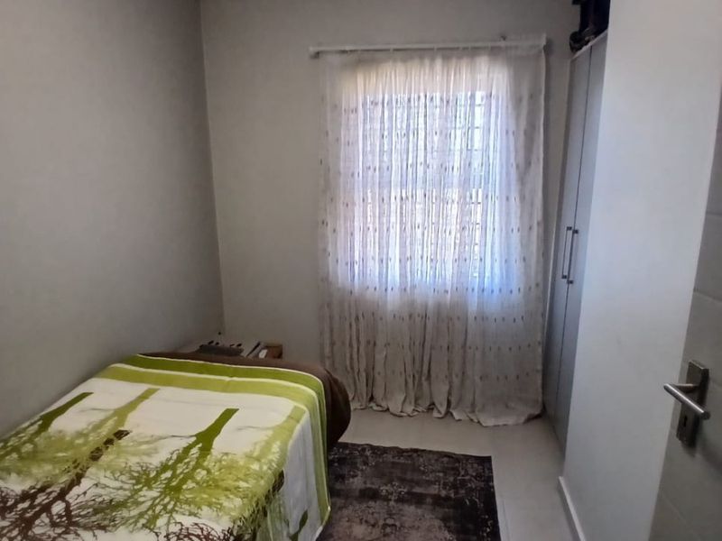 A compact bedroom featuring neutral wall finishes, tiled flooring, and a built-in wardrobe, providing a functional and well-maintained living space.