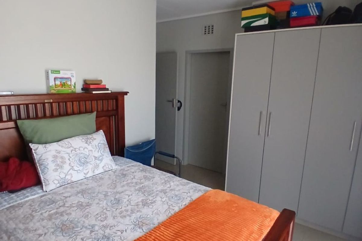 A functional bedroom featuring neutral wall tones, tiled flooring, and a built-in wardrobe providing ample storage space.