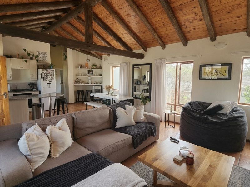 Open-plan living and kitchen area featuring exposed timber ceiling beams, tiled flooring, and a functional kitchen layout with built-in cabinetry.