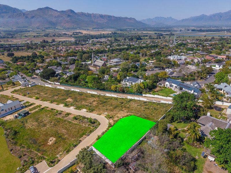 Aerial view of a vacant residential plot in a developed estate, featuring clear boundaries and surrounding mountain and suburban views.