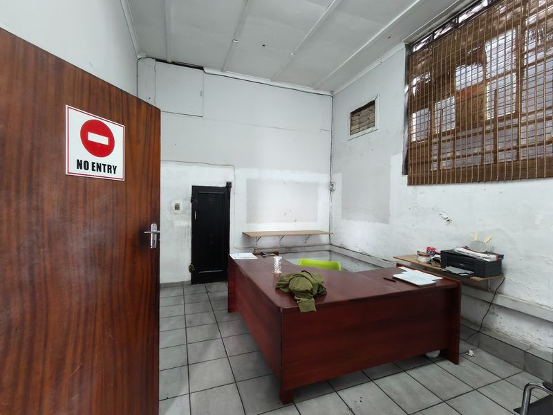 A functional office space featuring tiled flooring and security features, currently requiring cosmetic wall repairs and maintenance to improve the overall condition.