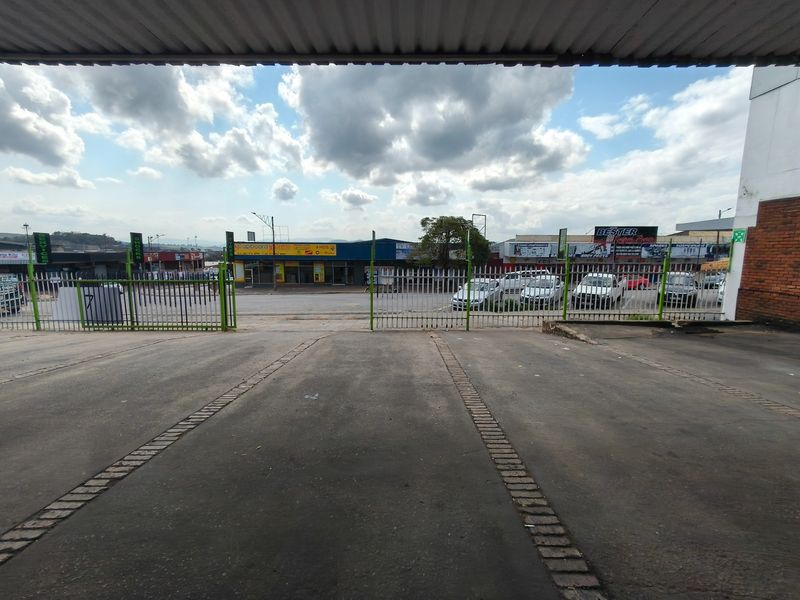 A view of the paved exterior parking area and entrance, featuring a secure metal gate and access to the commercial property frontage.