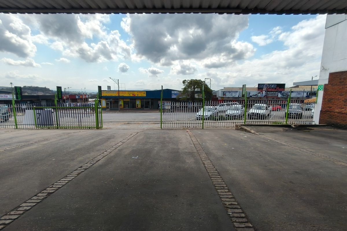 A view of the paved exterior parking area and entrance, featuring a secure metal gate and access to the commercial property frontage.
