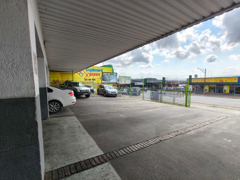 A covered exterior parking area with concrete paving and secure metal fencing, providing convenient access to the business premises.