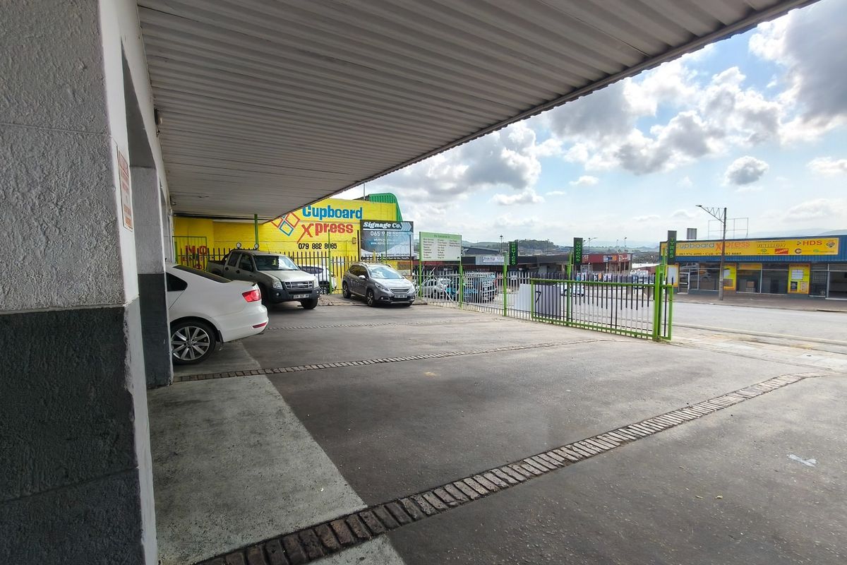 A covered exterior parking area with concrete paving and secure metal fencing, providing convenient access to the business premises.