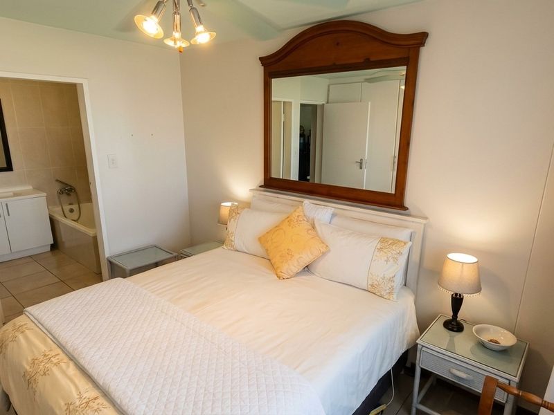 A bedroom featuring an attached en-suite bathroom with a vanity and tiled flooring, offering a functional layout with neutral finishes.