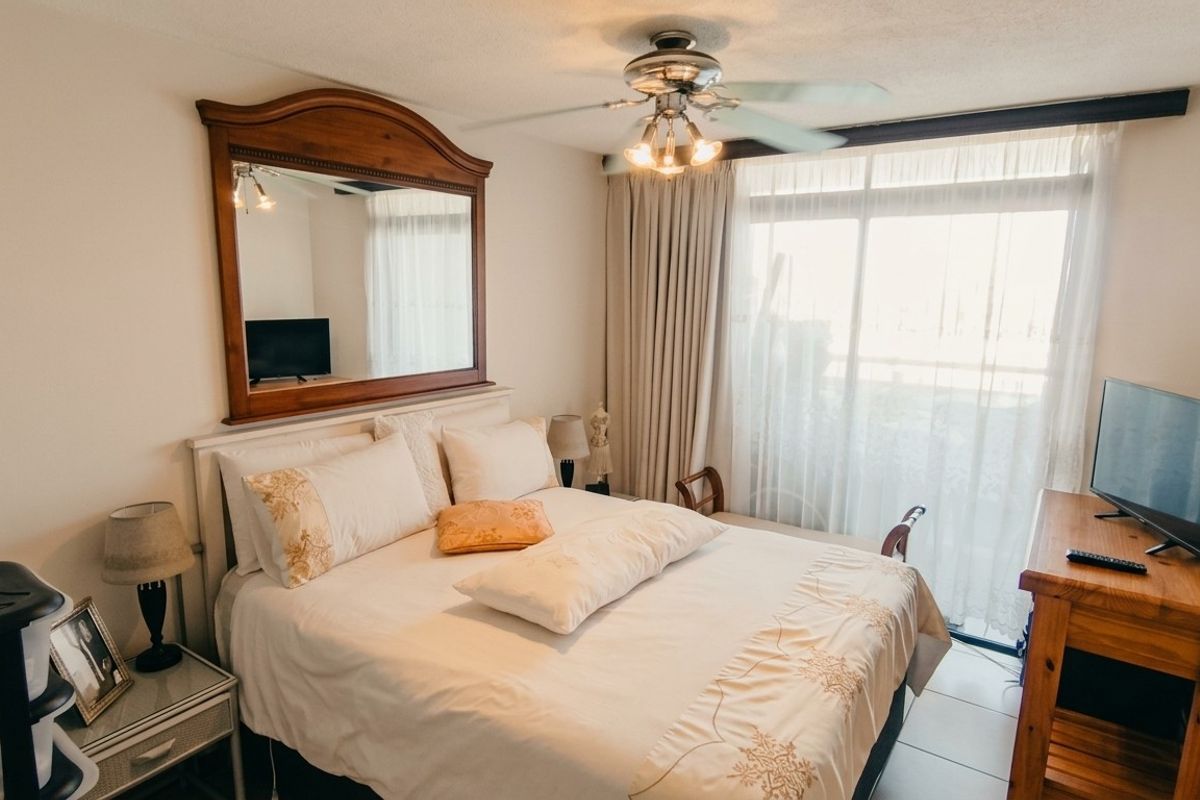 A bedroom featuring tiled flooring, a ceiling fan, and a sliding glass door providing natural light and access to the exterior.