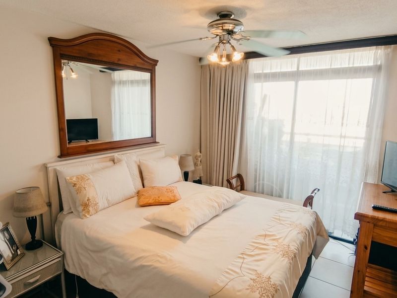 A bedroom featuring tiled flooring, a ceiling fan, and a sliding glass door providing natural light and access to the exterior.