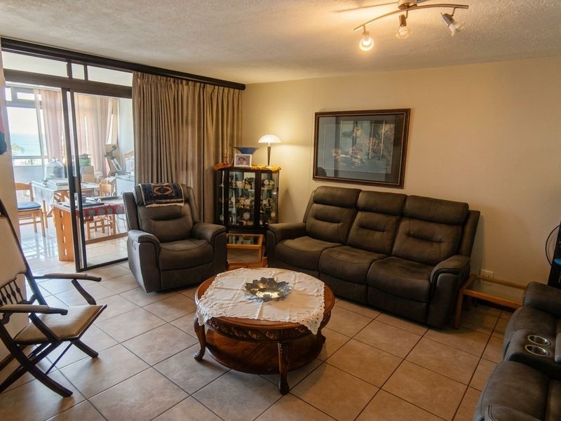 A spacious living room featuring tiled flooring and a large sliding glass door that provides access to an adjoining balcony area.