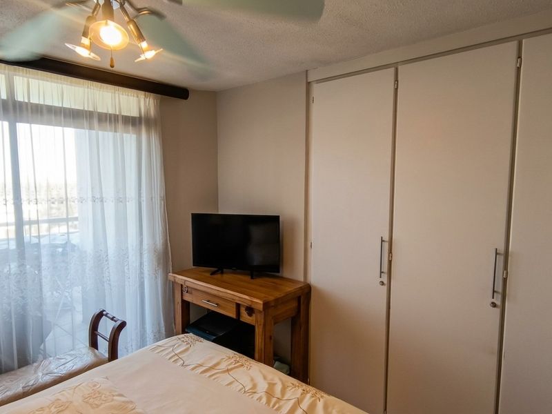 A bedroom featuring built-in cupboards, a ceiling fan, and a sliding glass door providing access to an outdoor area.