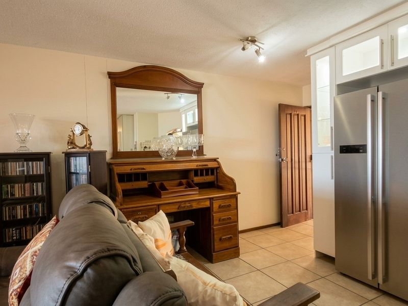 Open plan living area featuring tiled flooring, built-in cabinetry, and a solid wood door, offering a functional and versatile space.