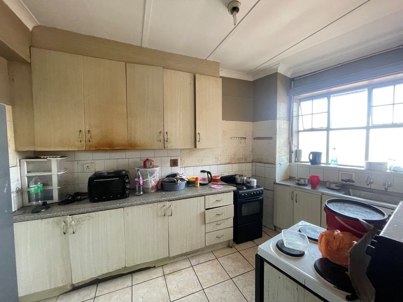 A dated kitchen featuring original laminate cabinetry, tiled backsplash, and tiled flooring, requiring significant cosmetic updates and modernization to improve functionality and aesthetic appeal.