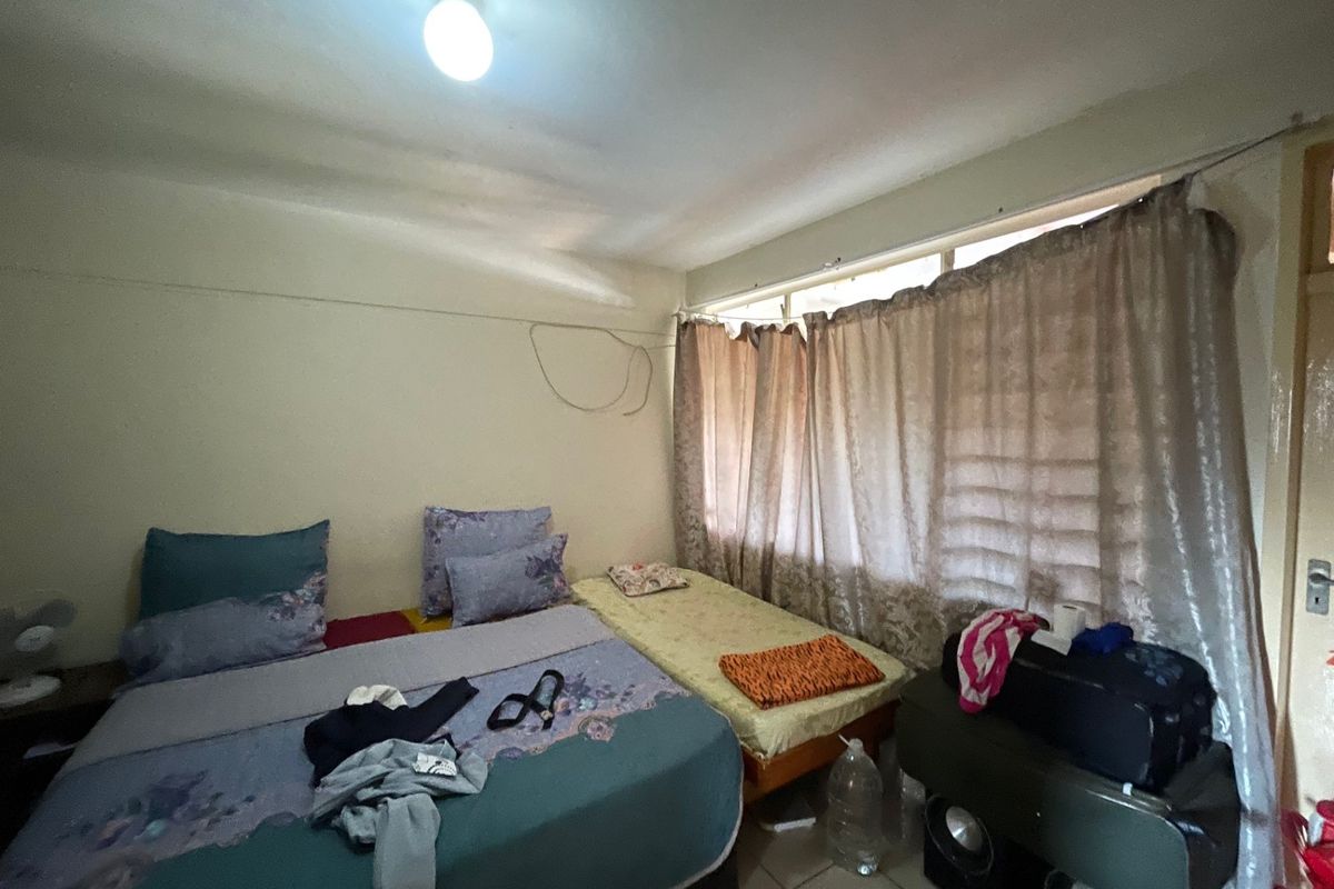 A bedroom featuring tiled flooring and a ceiling light fixture, currently requiring maintenance to address exposed wall wiring.
