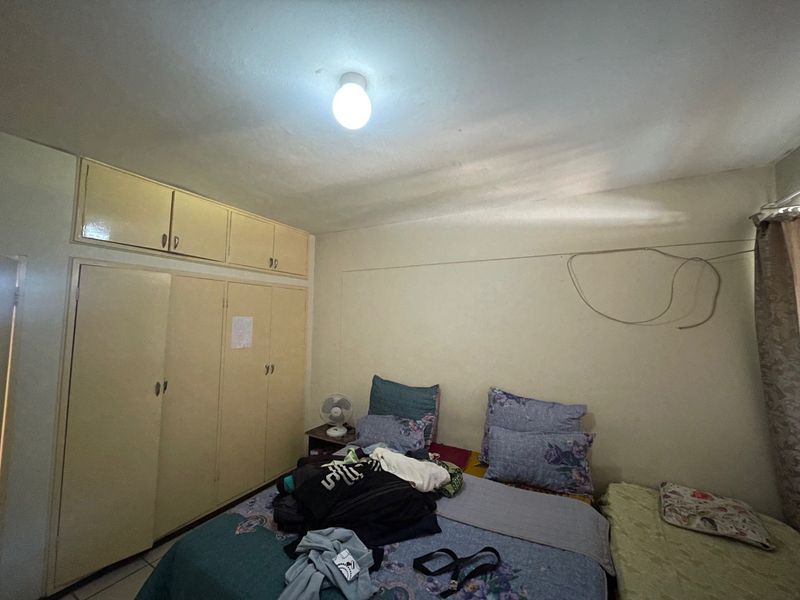 A bedroom featuring built-in cupboards with overhead storage units and a central ceiling light fixture.