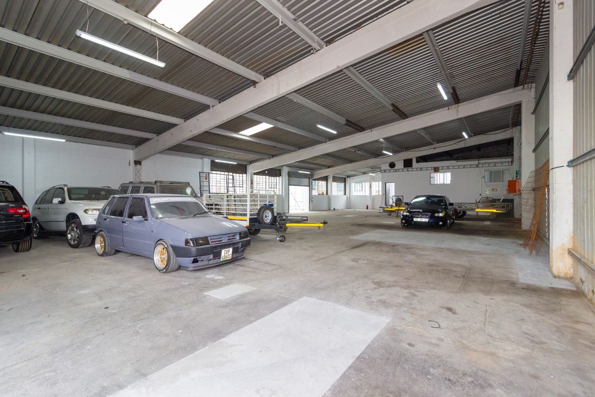 Spacious industrial garage featuring high exposed steel ceilings, fluorescent lighting, and durable concrete flooring, suitable for storage or workshop use.