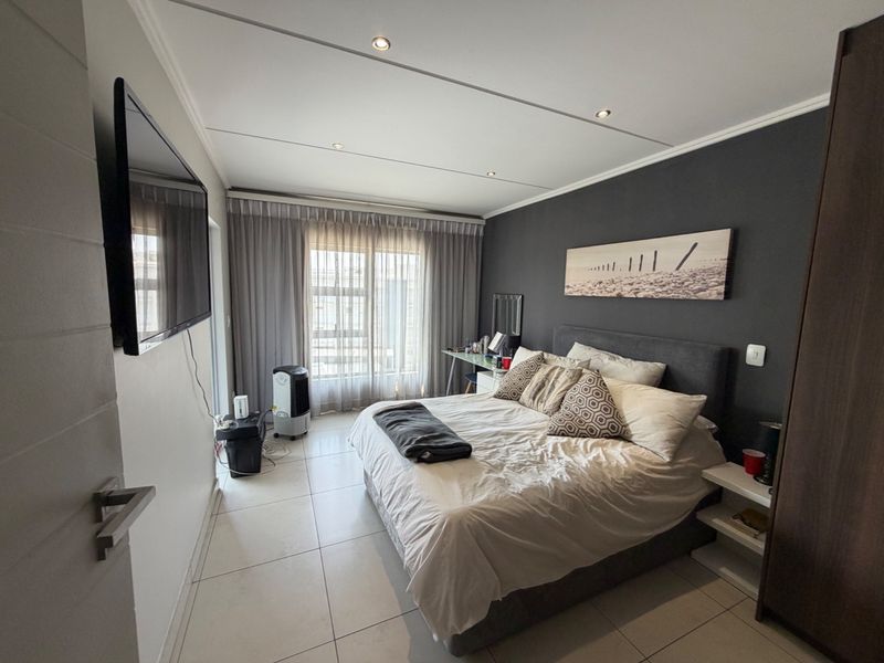 A well-maintained bedroom featuring tiled flooring, recessed downlighting, and a sliding glass door providing natural light.