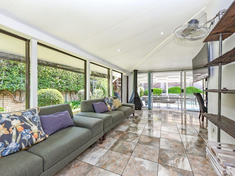 Spacious enclosed patio featuring tiled flooring, a modern freestanding fireplace, and large sliding glass doors providing seamless access to the outdoor garden area.