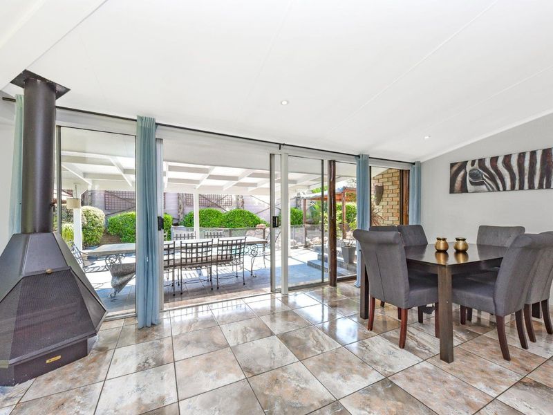 Open plan living area featuring a freestanding fireplace, tiled flooring, and large sliding glass doors providing seamless access to the outdoor patio.