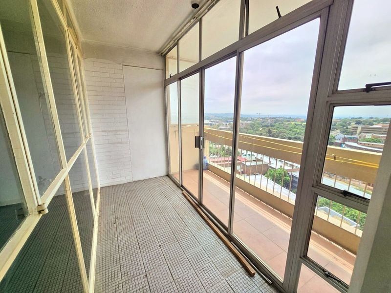An enclosed balcony featuring tiled flooring, sliding glass doors, and expansive views, offering a versatile space for potential renovation or outdoor living.