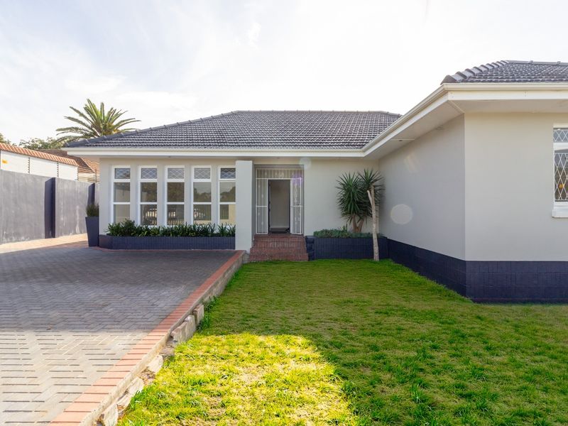 Front exterior view of the office property featuring a paved driveway, well-maintained lawn, tiled roof, and secure entrance with security gate.