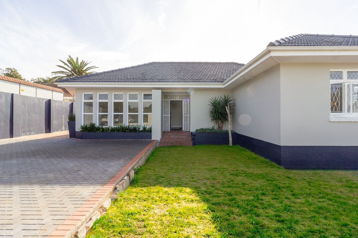 Front exterior view of the office property featuring a paved driveway, well-maintained lawn, tiled roof, and secure entrance with security gate.