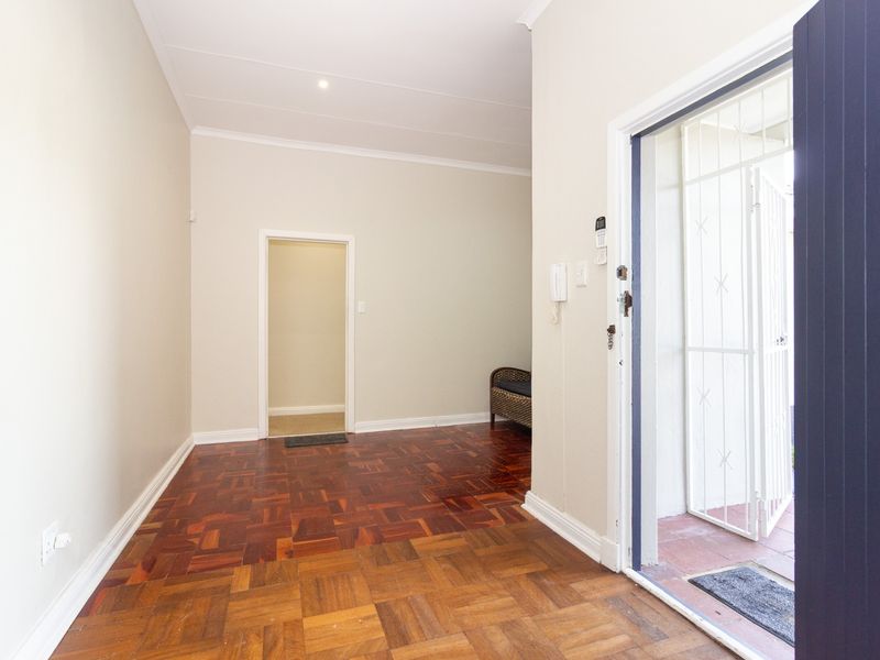 A bright and spacious entrance hall featuring classic parquet flooring, a secure entrance gate, and an integrated intercom system.