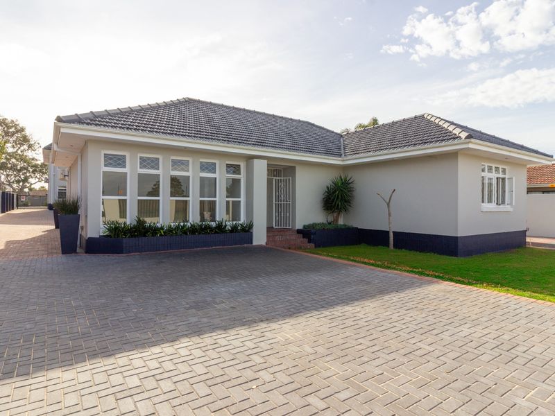 A well-maintained office building exterior featuring a paved driveway, tiled roof, and secure entrance with built-in planters.