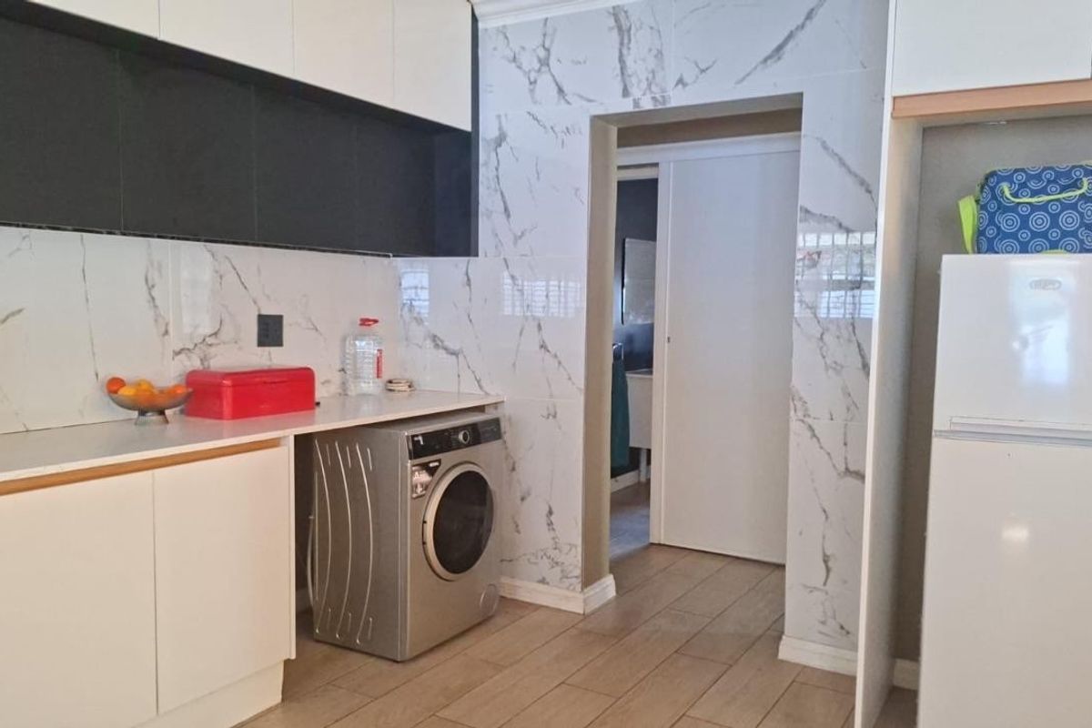 Modern kitchen featuring marble-look wall tiling, sleek built-in cabinetry, and durable laminate flooring with a convenient sliding door access.