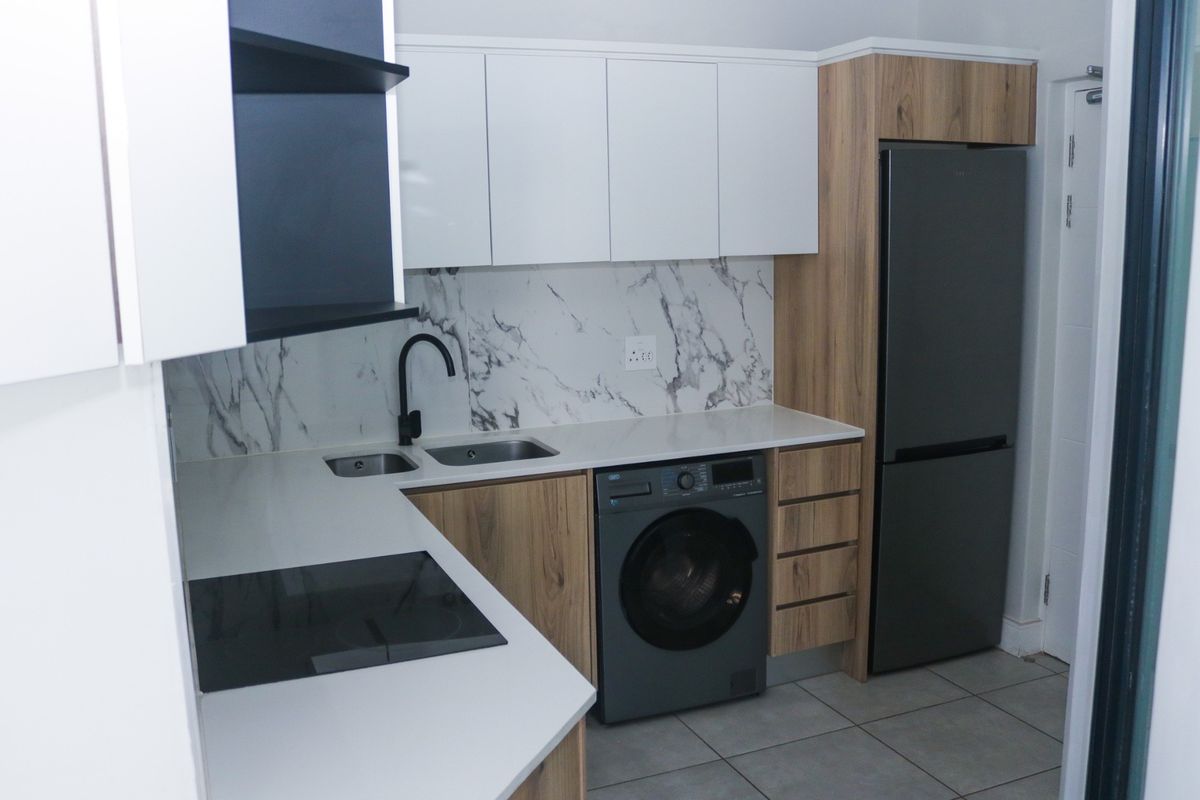Modern kitchen featuring sleek white and wood-grain cabinetry, marble-look splashback, stone countertops, and integrated appliances.