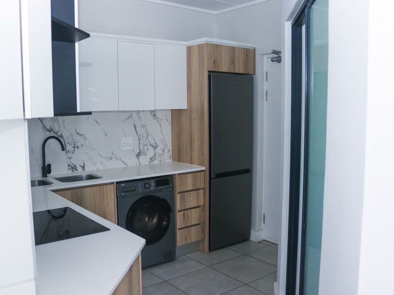 Modern kitchen featuring sleek white and wood-grain cabinetry, marble-look splashback, integrated appliances, and high-quality finishes throughout.