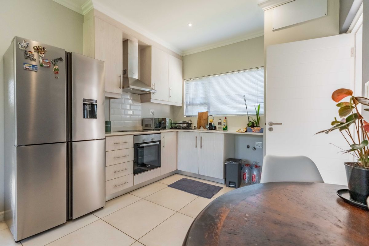 A functional kitchen featuring light wood cabinetry, subway tile backsplash, built-in oven and hob, and tiled flooring with a dedicated space for appliances.
