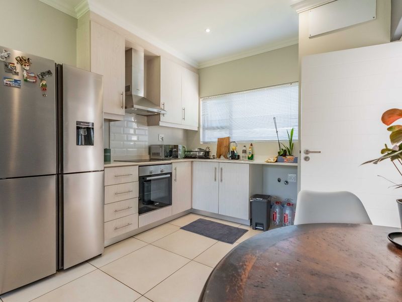 A functional kitchen featuring light wood cabinetry, subway tile backsplash, built-in oven and hob, and tiled flooring with a dedicated space for appliances.