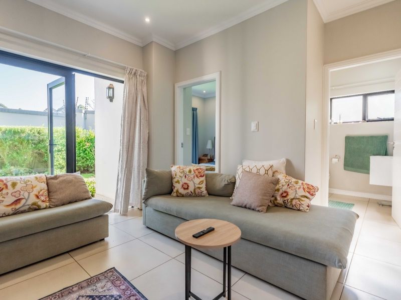 Bright living room featuring tiled floors, recessed lighting, and large aluminium sliding doors providing direct access to the outdoor area.