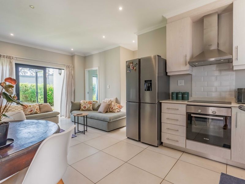 Open-plan living area featuring a modern kitchen with built-in appliances, tiled floors, and sliding doors leading to an outdoor space.