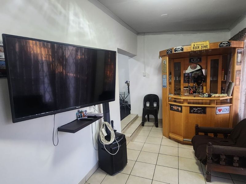 A dedicated bar area featuring tiled flooring and a built-in wooden bar unit, providing a functional space for entertainment.