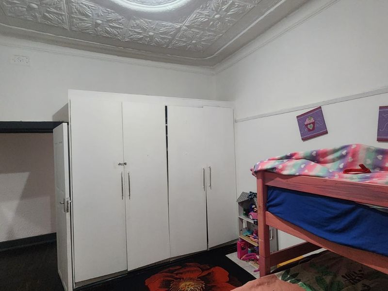 Bedroom featuring a classic pressed metal ceiling with an ornate ceiling rose, picture rails, and a large built-in wardrobe.