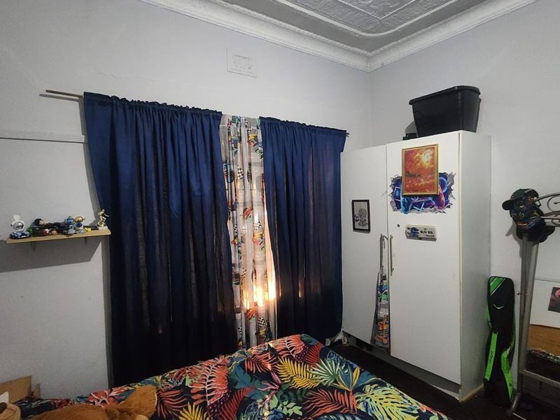 A bedroom featuring a classic pressed metal ceiling with decorative cornice and a built-in wardrobe.