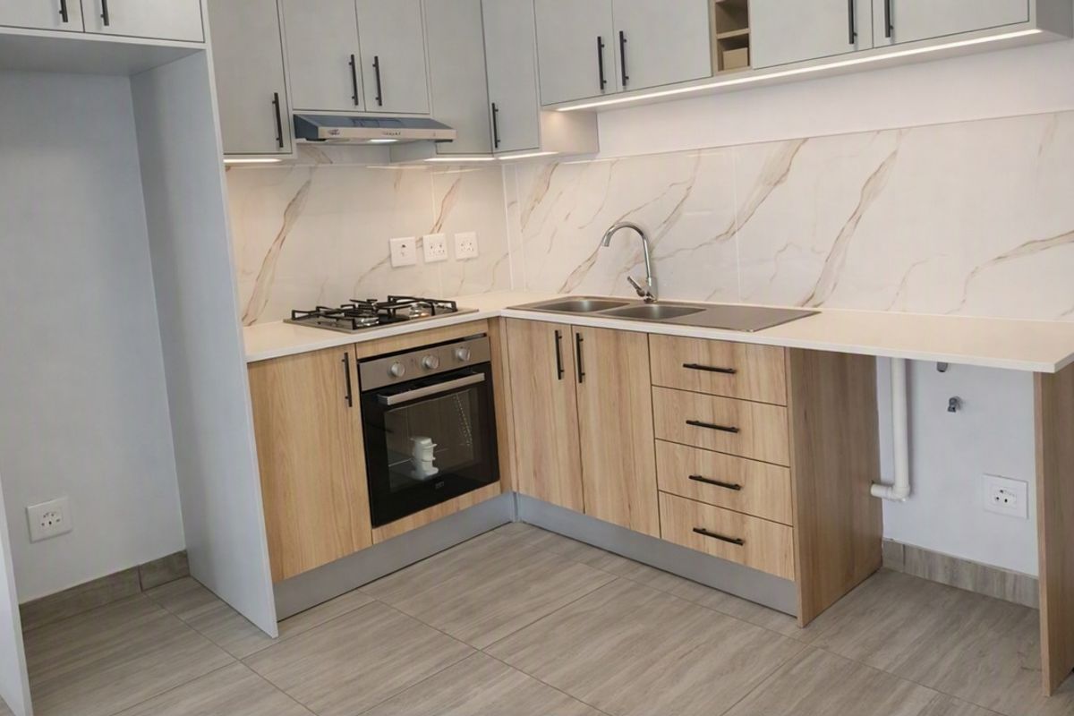 Modern kitchen featuring light wood cabinetry, marble-look splashback, gas hob, built-in oven, and integrated sink with contemporary finishes.