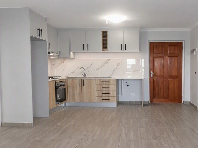 Modern kitchen featuring light wood and grey cabinetry, marble-look splashback, built-in oven, gas hob, and tiled flooring in an open-plan layout.