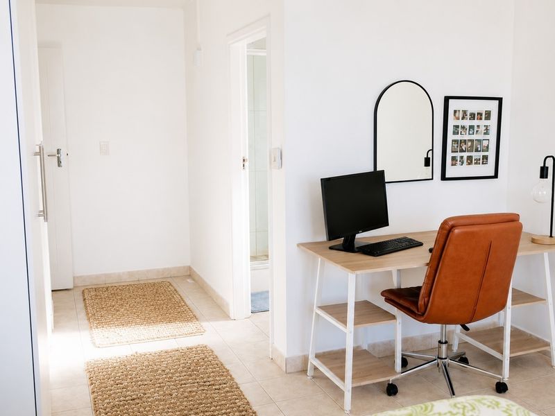 A bright and functional home office space featuring neutral tiled flooring and direct access to an adjoining room.