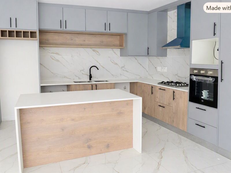 Modern kitchen featuring two-tone cabinetry, stone countertops, a central island, built-in gas hob, oven, and elegant marble-look tile finishes throughout.