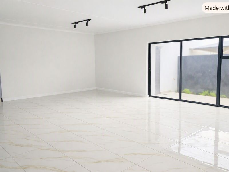 Spacious open-plan living area featuring polished marble-look floor tiles, modern black track lighting, and large sliding doors leading to an outdoor patio.