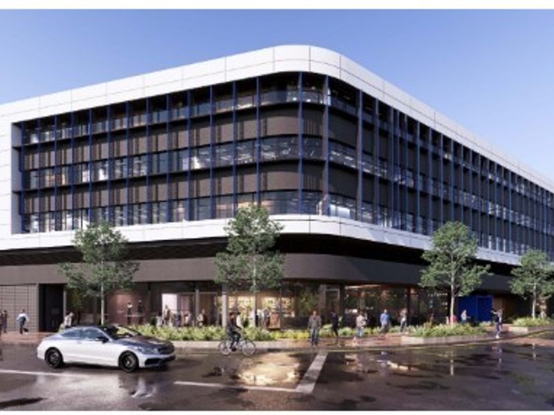 A modern multi-story office building featuring a contemporary facade with extensive glazing and integrated sun shading elements at street level.
