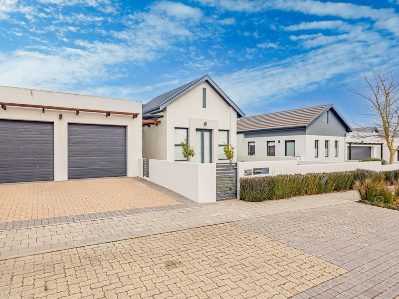 Modern residential property featuring a double garage, paved driveway, and clean architectural lines with a well-maintained front boundary wall and entrance.