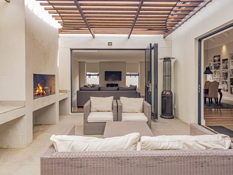 Covered outdoor patio featuring a built-in fireplace, timber pergola, and seamless access to the indoor living area through large bi-fold doors.