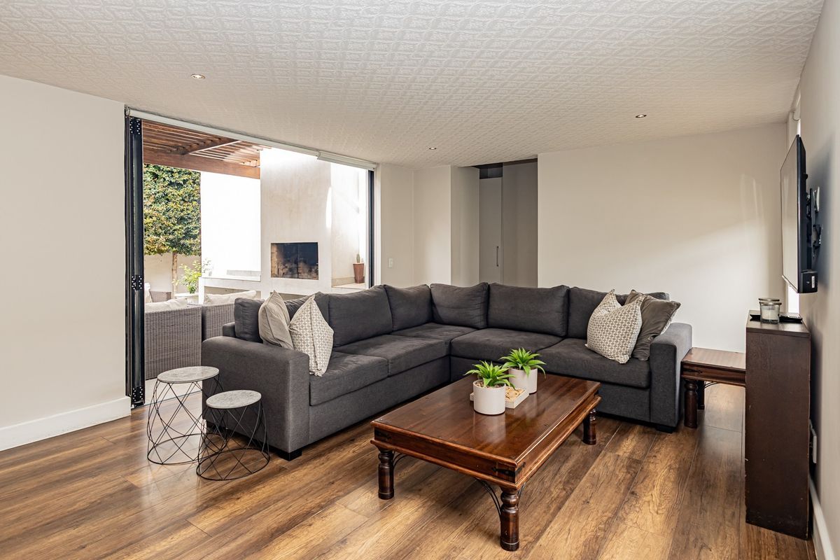 Spacious living room featuring laminate flooring, textured ceiling, and large stacking glass doors that open onto an outdoor patio area with a built-in fireplace.