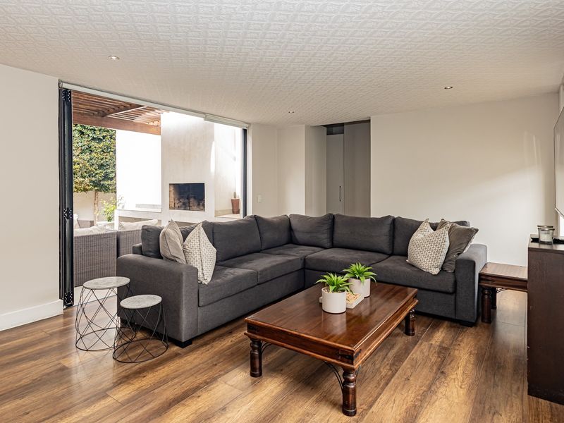 Spacious living room featuring laminate flooring, textured ceiling, and large stacking glass doors that open onto an outdoor patio area with a built-in fireplace.